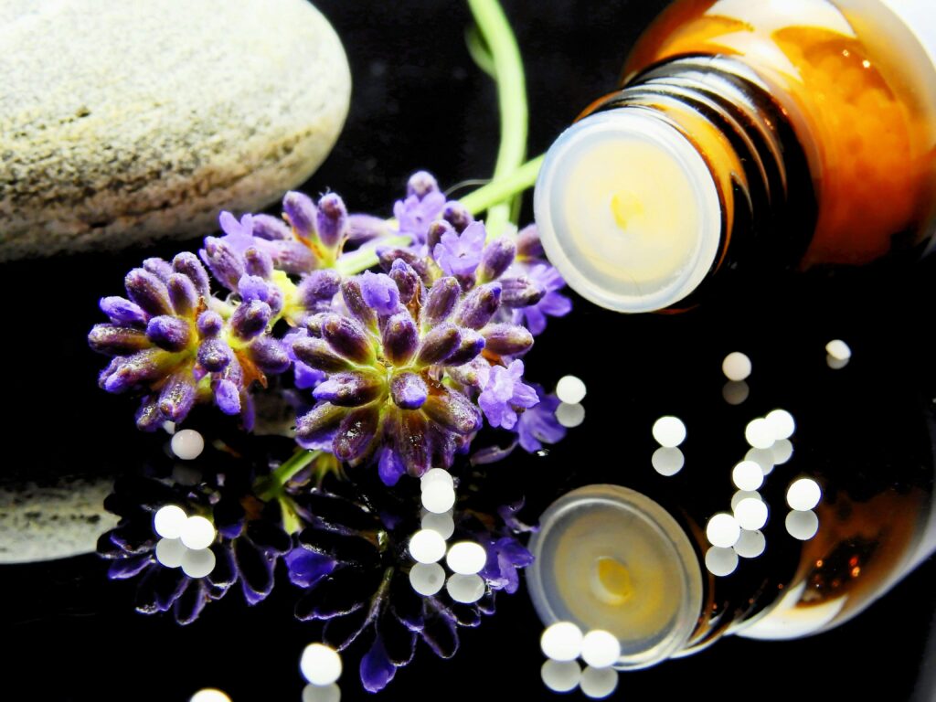 homeopathic bottle with pellets next to purple flowers -Radiant Homeopathy - homeopathic remedies